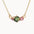 Gold necklace with a green gemstone and pink stones on a white background