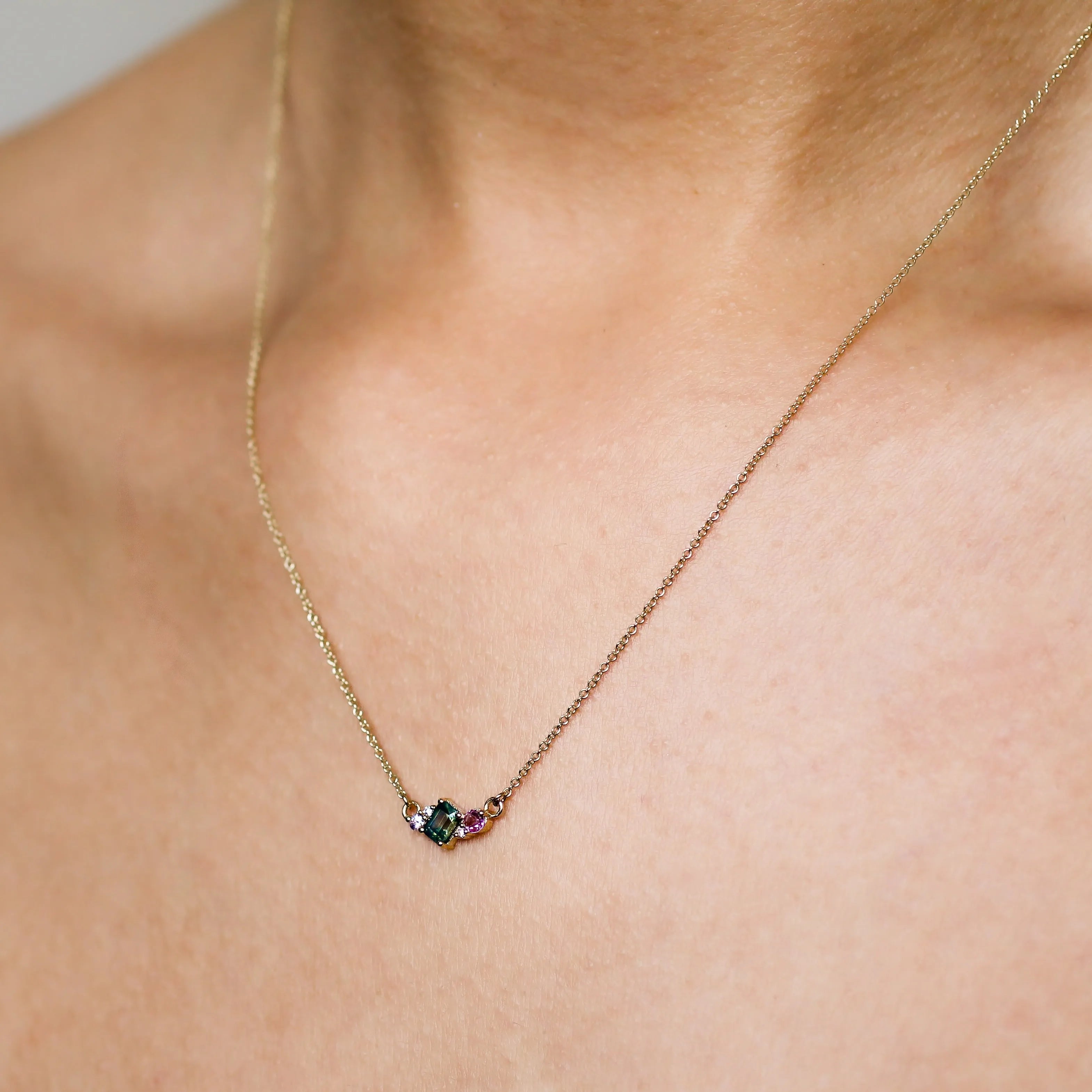 close up of green and pink sapphire necklace being worn