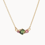 Necklace with a green gemstone and pink stones on a gold chain against a white background