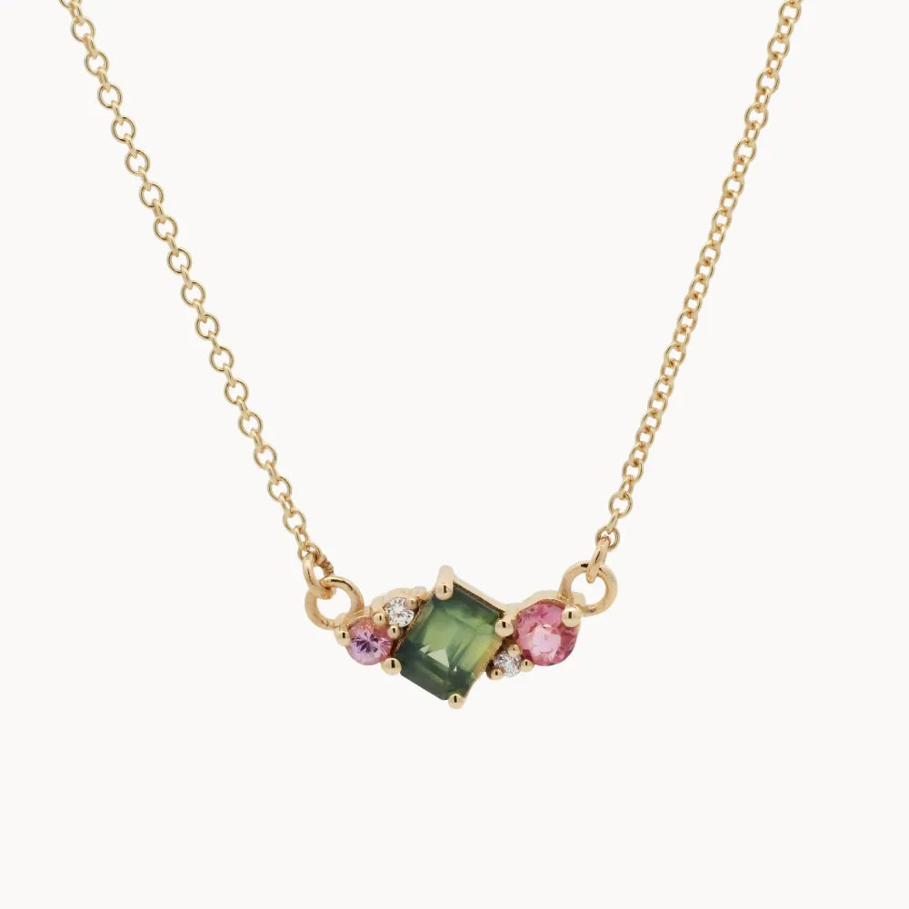 Necklace with a green gemstone and pink stones on a gold chain against a white background
