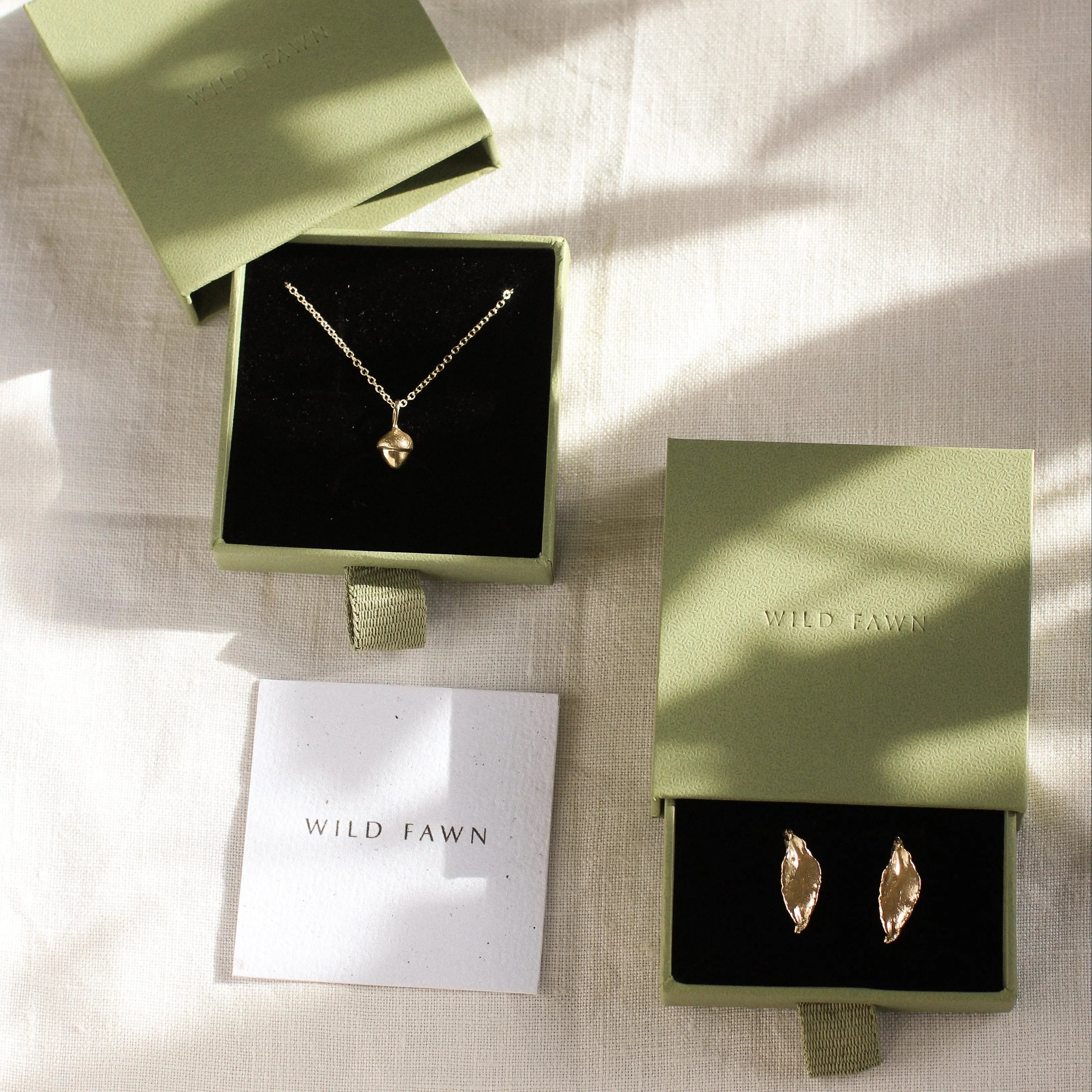 green gift boxes with gold acorn necklace and leaf earring with Wild Fawn care card