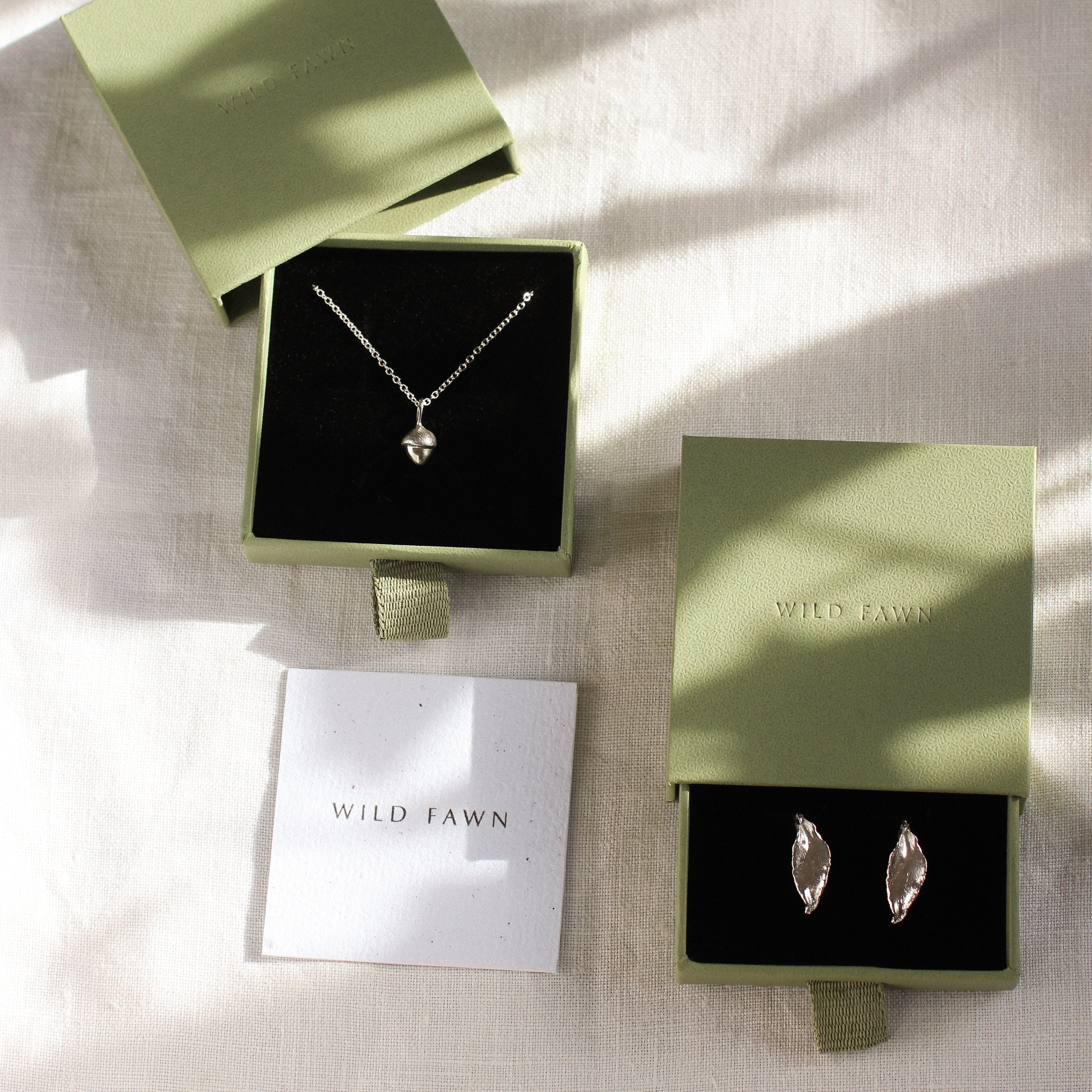 green gift boxes with acorn necklace and leaf earrings in silver with wild fawn care card
