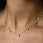 close up of neck wearing diamond drop necklace with 2 beads and 3 diamonds