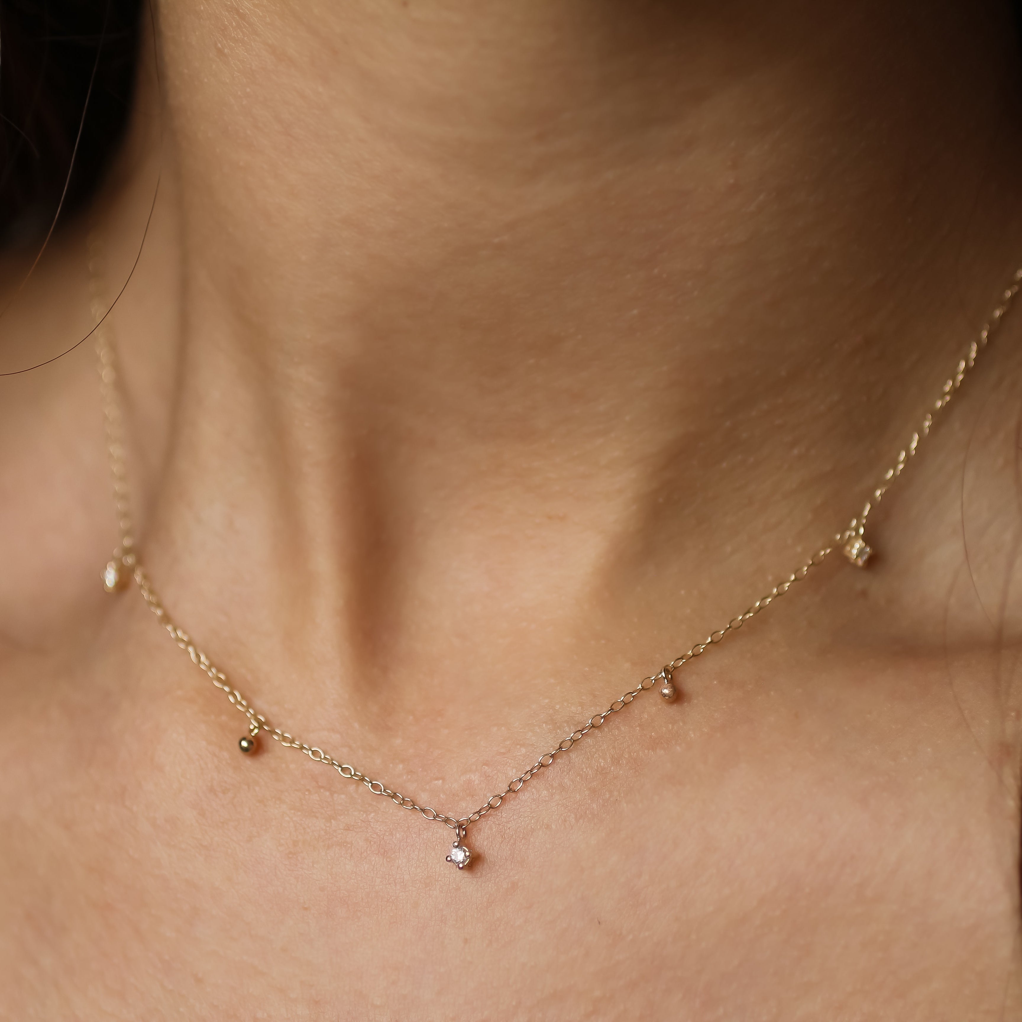 close up of neck wearing diamond drop necklace with 2 beads and 3 diamonds