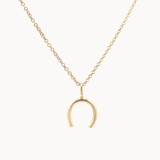 Gold horseshoe pendant necklace on a white background