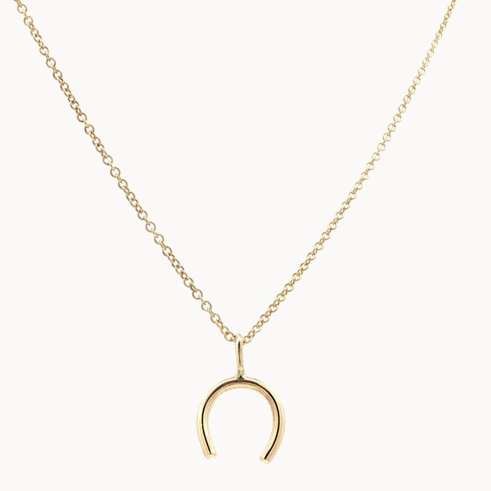 Gold necklace with a horseshoe pendant on a white background