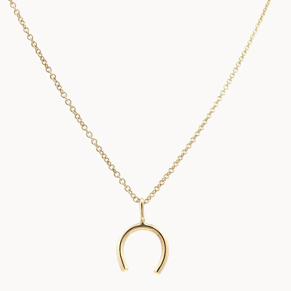 Gold necklace with a horseshoe pendant on a white background