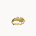 A single gold ring with a textured, organic, wavy shape, photographed on a clean off-white background.