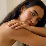 woman smiling to camera resting her arms on her shoulder wearing lowfit green sapphire trilogy engagement ring