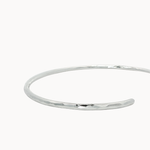 close up of hammered texture on open silver bangle on a white background