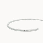 close up of hammered texture on open silver bangle on a white background