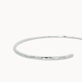 close up of hammered texture on open silver bangle on a white background