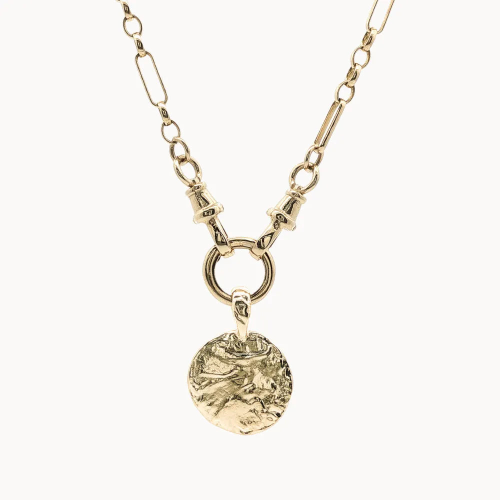 Gold necklace with a round textured pendant on a white background