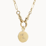 Gold chunky chain necklace with a round pendant engraved 'with love x' on a white background