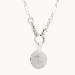 Silver chunky necklace with a round engraved pendant on a white background