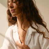 Woman wearing a white shirt and silver heart necklace with a blurred background