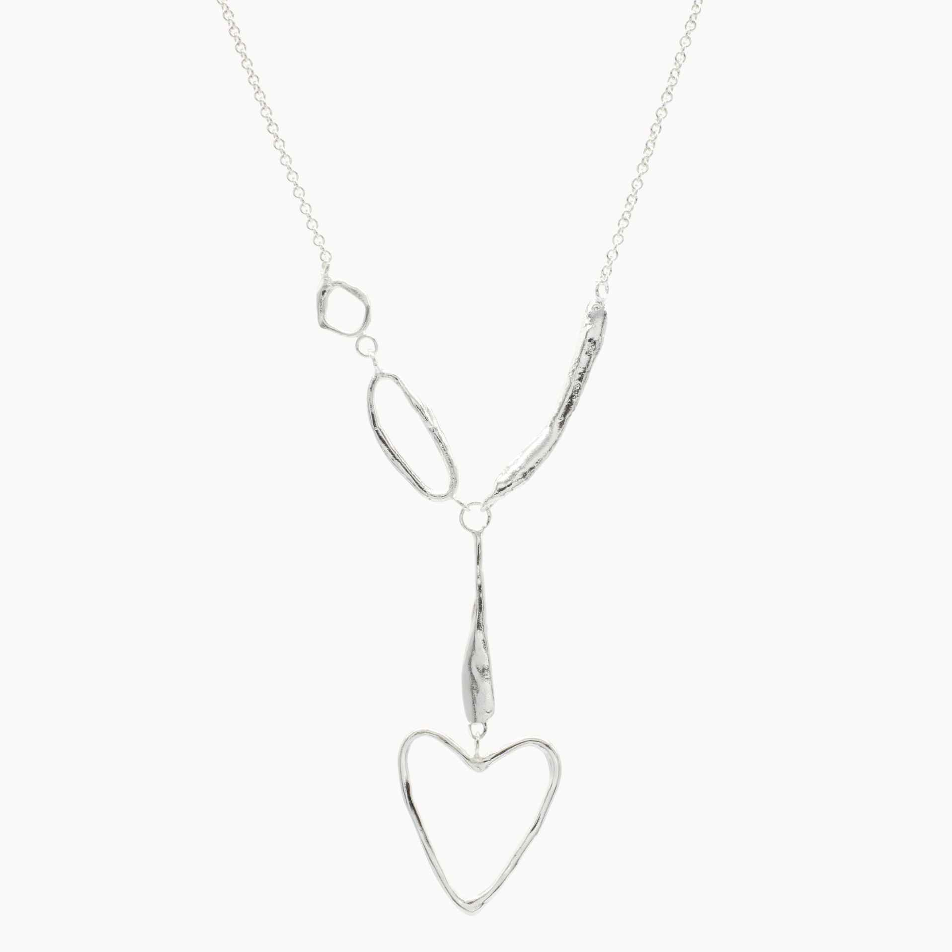 silver necklace with organic shapes and heart pendant on white background