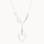 silver necklace with organic shapes and heart pendant on white background