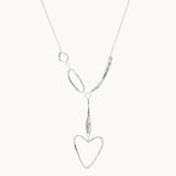 silver necklace with organic shapes and heart pendant on white background