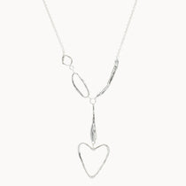 silver necklace with organic shapes and heart pendant on white background