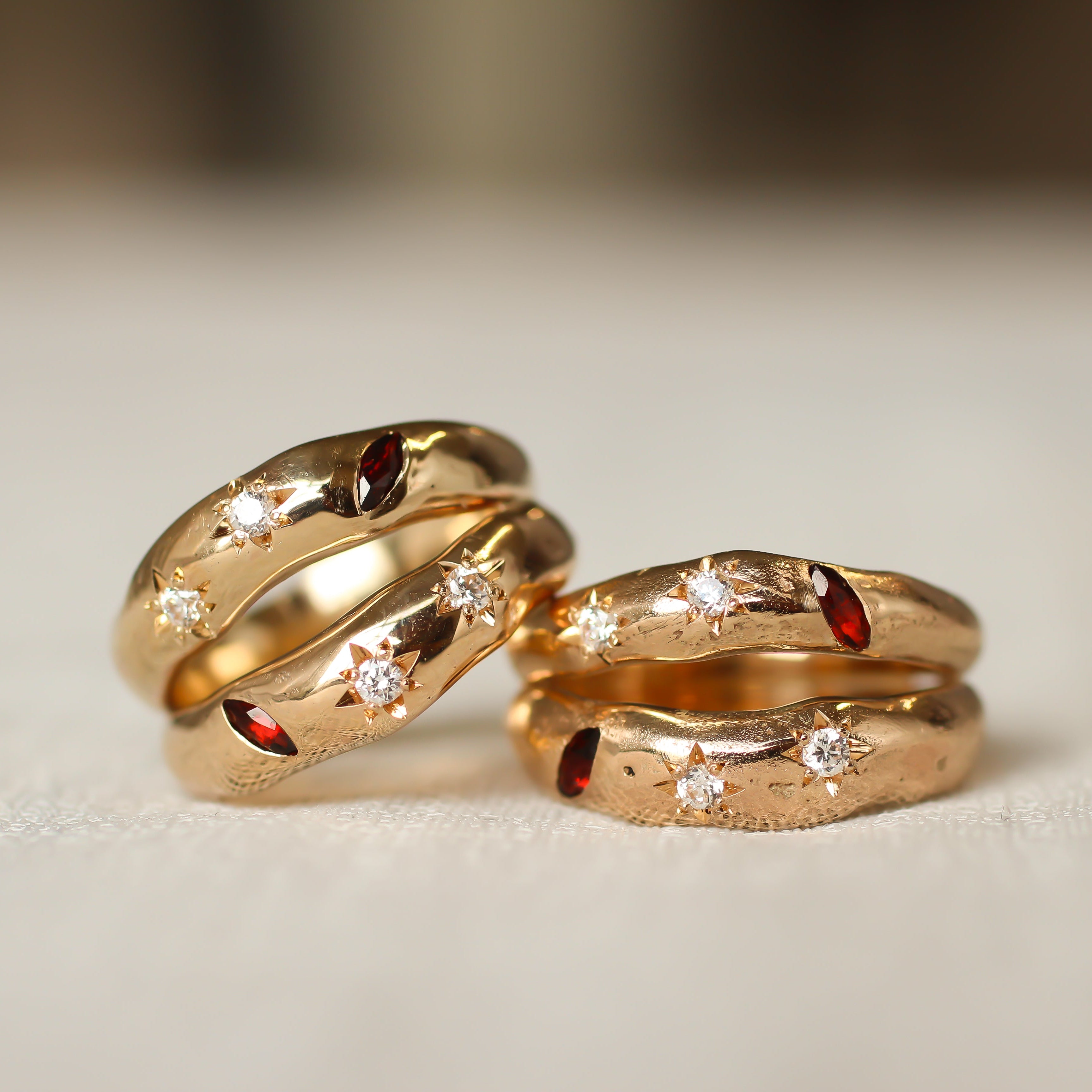 Two gold rings with embedded gemstones on a light background