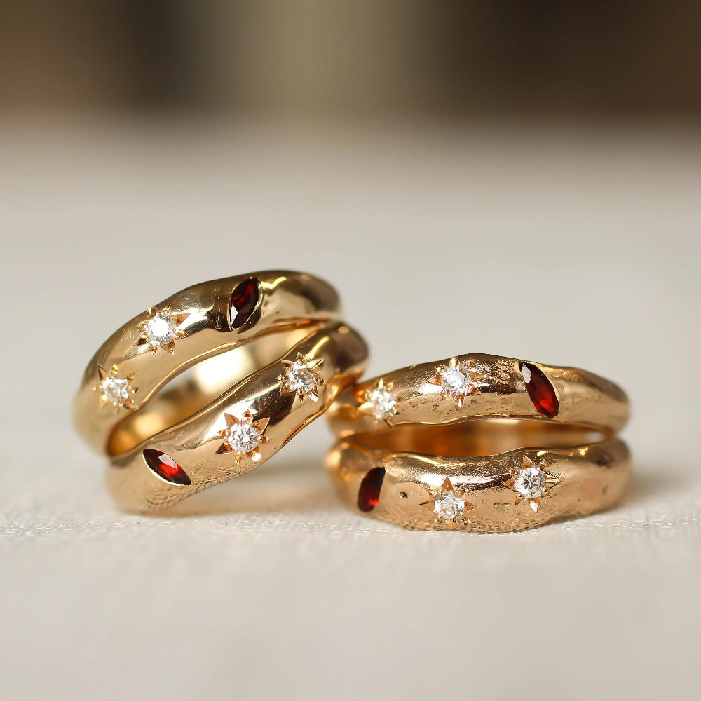 Two gold rings with embedded gemstones on a light background