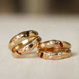Two gold rings with embedded gemstones on a light background