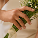 Person holding a bouquet of flowers with a focus on the hands wearing a hexagon sapphire engagement ring holding a bouquet.