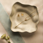 ceramic dish with diamond necklace and sun shaped stud earrings with flower and ribbon