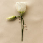 white gold hook earrings with diamonds on a white rose stem against a beige background