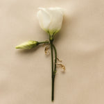 White rose with gold hook diamond earrings on a beige fabric background