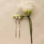 Pair of silver-toned gold earrings with diamond, star and molten detailing on a white rose step with a beige background