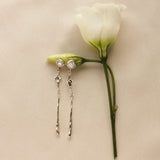 Pair of silver-toned gold earrings with diamond, star and molten detailing on a white rose step with a beige background