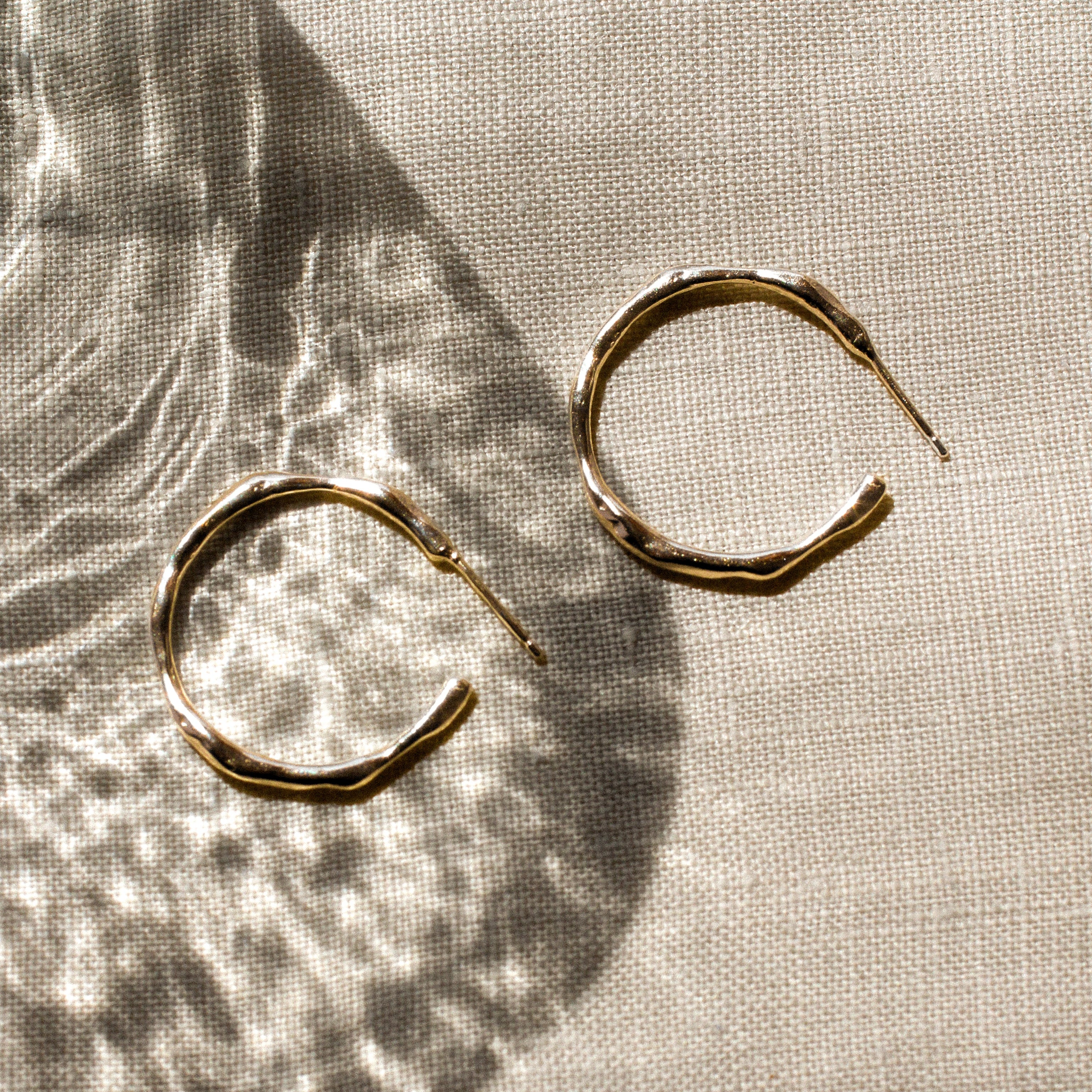 Gold hoop earrings on a textured beige fabric surface
