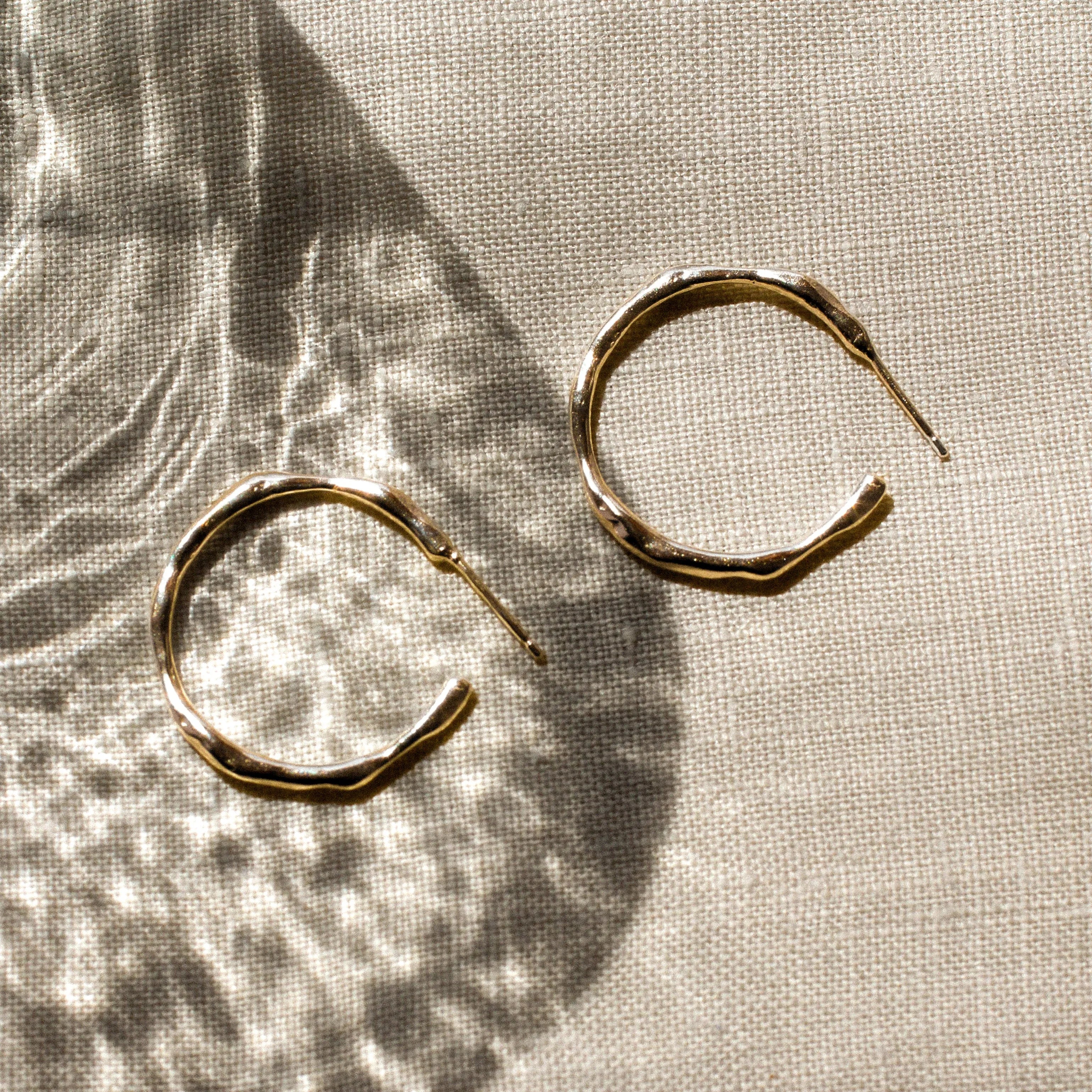 Gold hoop earrings on a textured beige fabric surface