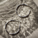 Pair of silver hoop earrings on a textured fabric surface