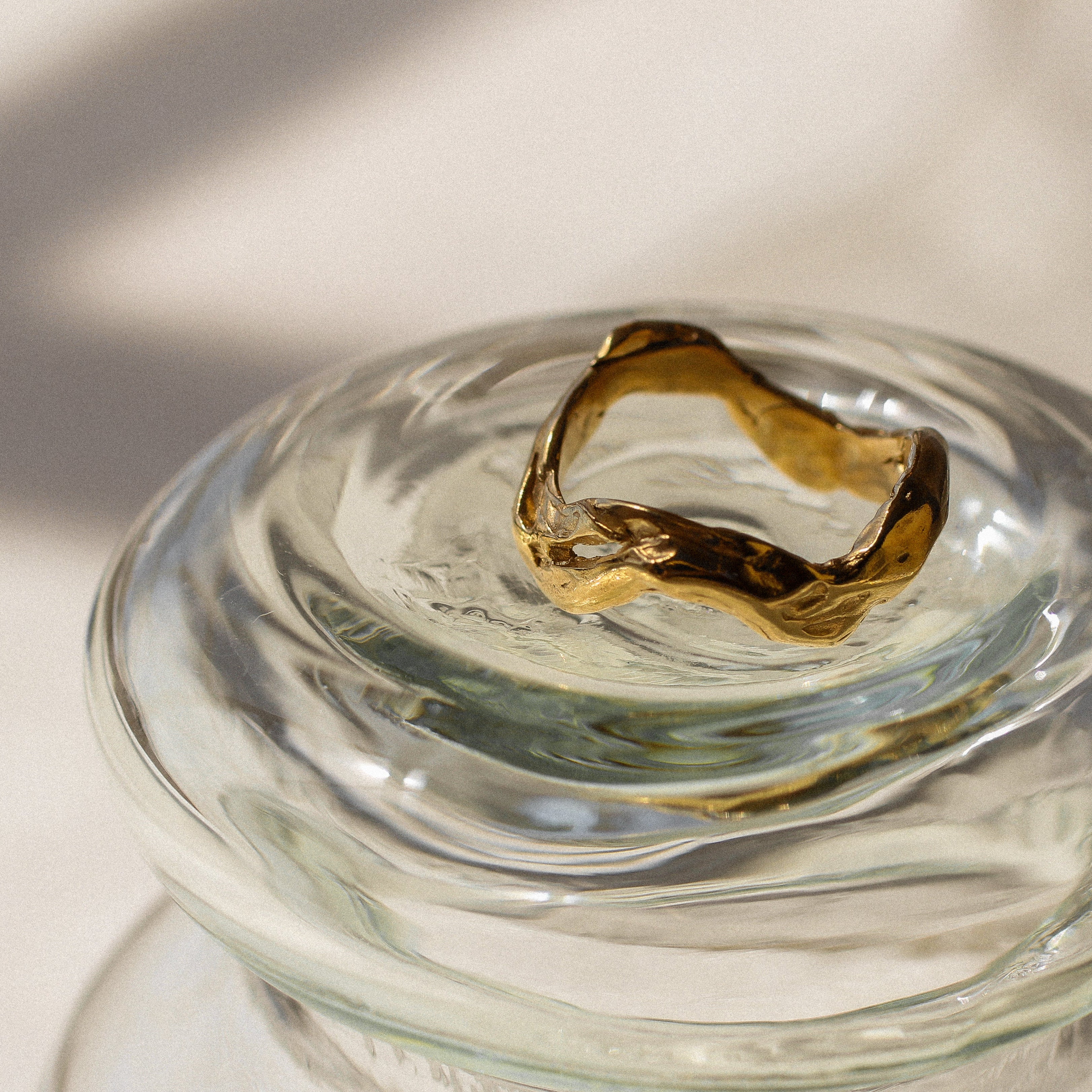 Gold ring on a clear glass dish with a blurred background