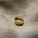 Gold ring on a textured beige fabric background