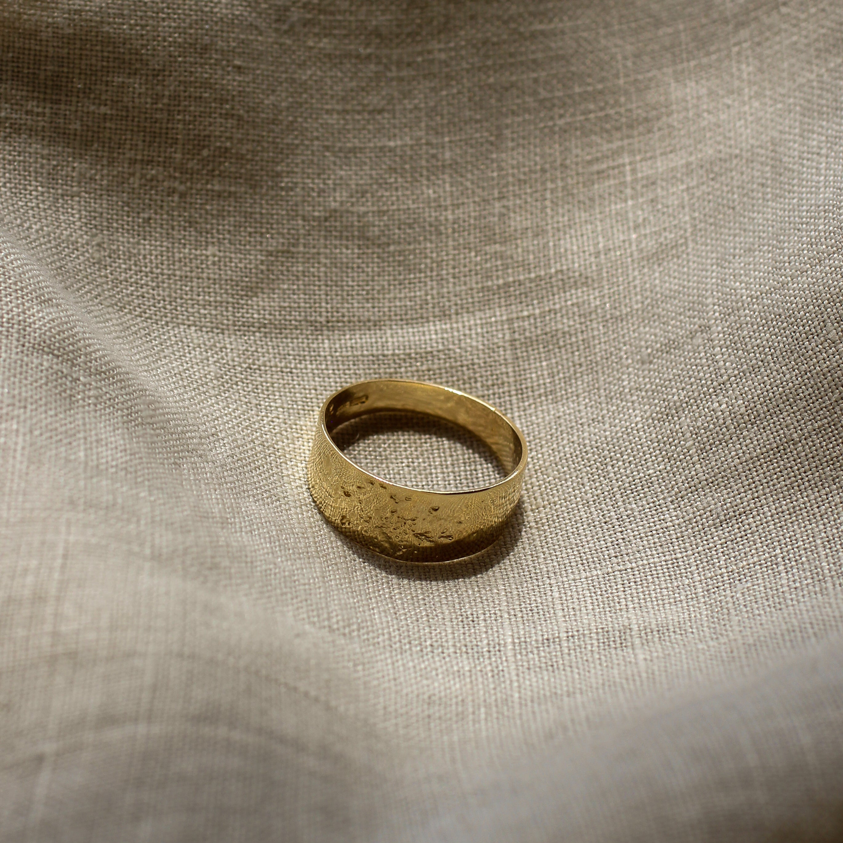 Gold ring on a textured beige fabric background