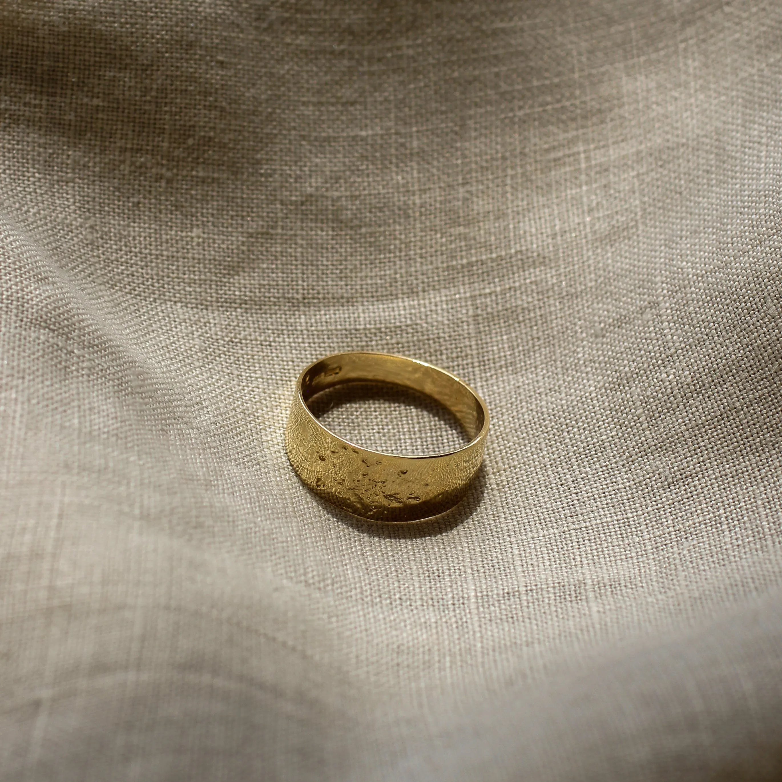 Gold ring on a textured beige fabric background