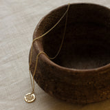 Gold necklace with a pendant on a textured surface