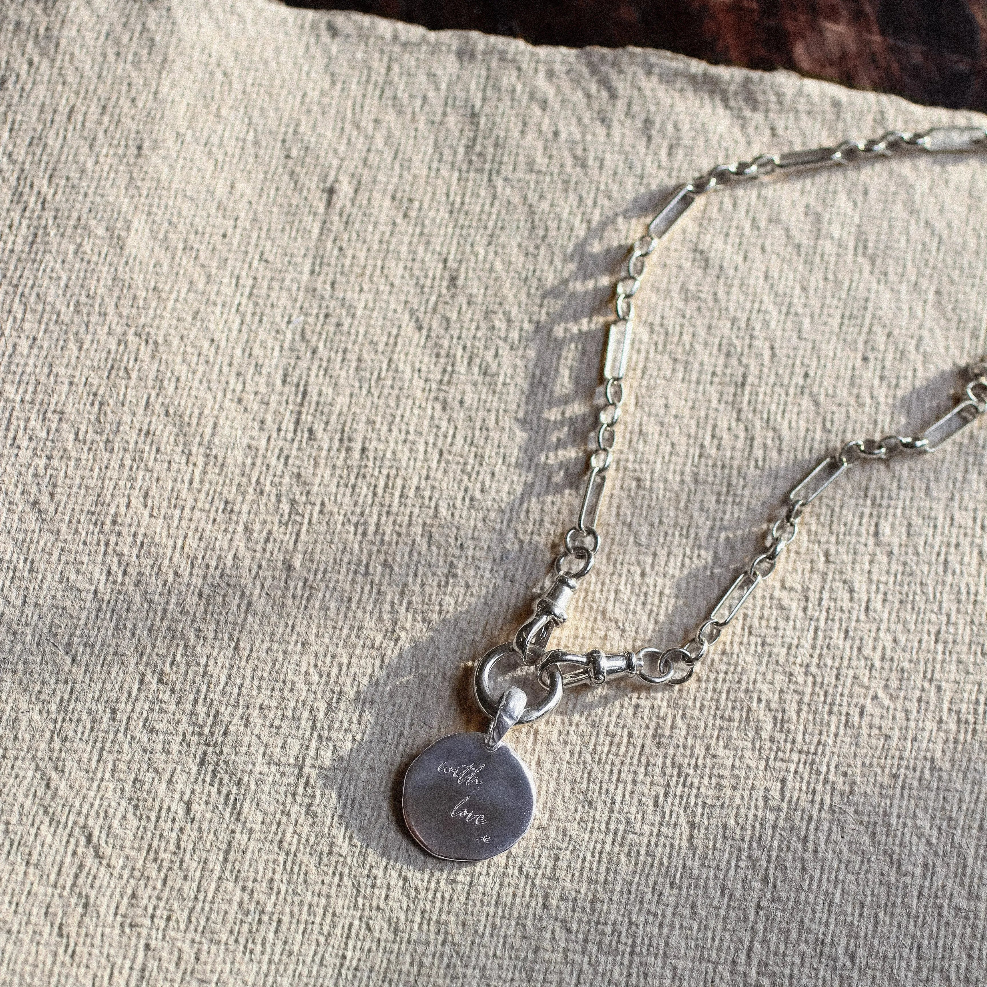 Silver necklace with a pendant on a textured beige surface