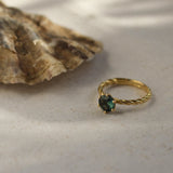 twisted blue sapphire engagement ring next to an oyster shell