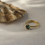 twisted blue sapphire engagement ring next to an oyster shell