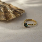 twisted blue sapphire engagement ring next to an oyster shell