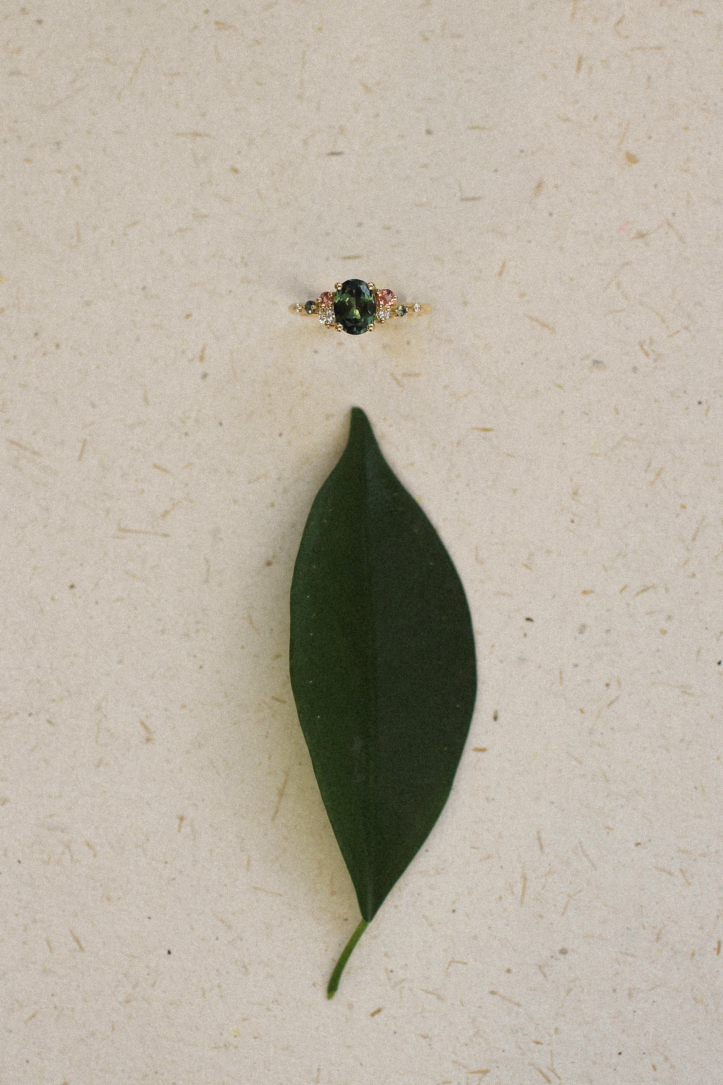 Green leaf and ring on a textured beige surface