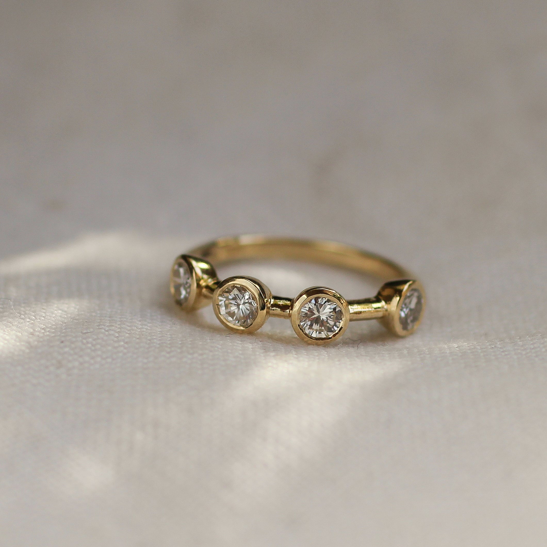 Gold ring with three diamonds on a textured fabric background