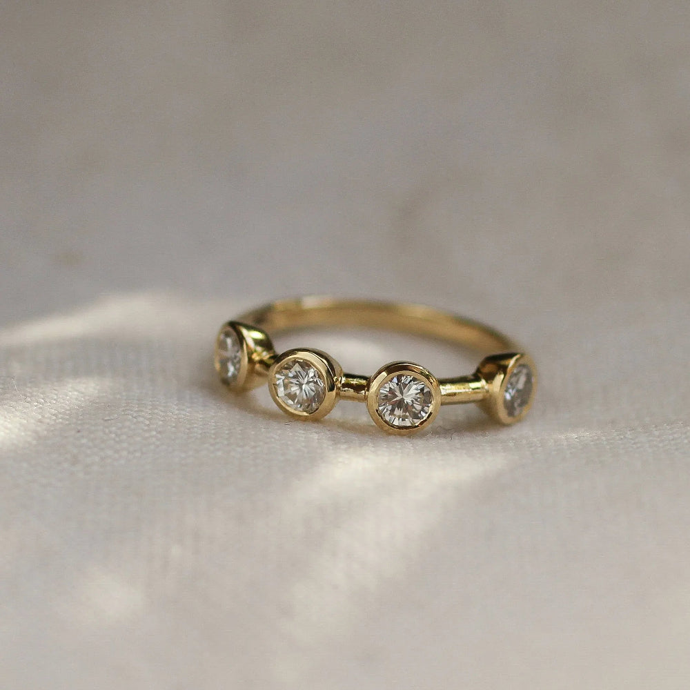 Gold ring with three diamonds on a textured fabric background