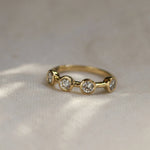 Gold ring with three diamonds on a textured fabric background