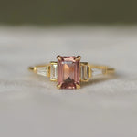 Gold ring with a pink gemstone on a white surface